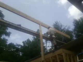 Carpenter setting a ridge beam over a new addition frame — Ice Dam Removal by Roofing Brothers in Mc Intosh