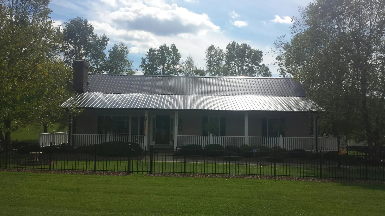 Gray metal roof on a brick ranch with a full width front porch — Gutter Guard Installation work by our crew in Mc Intosh
